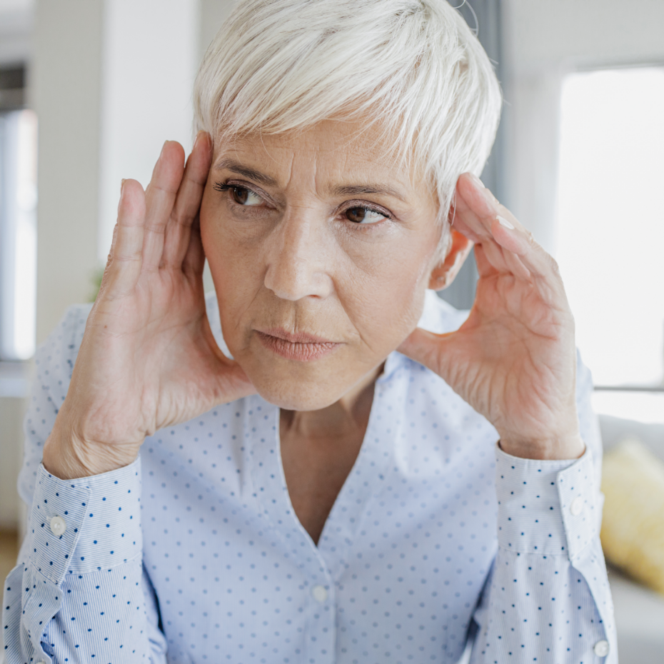 Frau fasst sich an den Kopf wegen störender Ohrgeräusche.